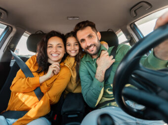 Automobile rent and purchase. Excited family embracing sitting in new car driving and enjoying road trip on vacation