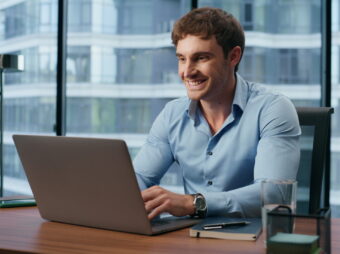 Happy boss working laptop in city view office. Manager chatting social media