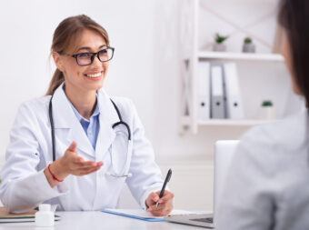 Lady Doctor Talking With Unrecognizable Patient During Appointment In Office