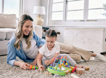 Shot of a mom sitting with her daughter while she plays with her toys.